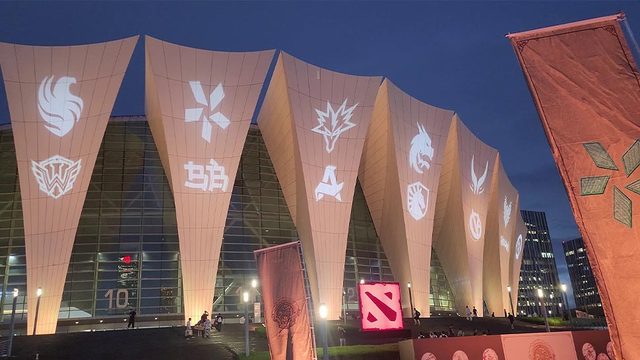 Dota 2 team logos projected at night against the Shanghai Oriental Sports Center